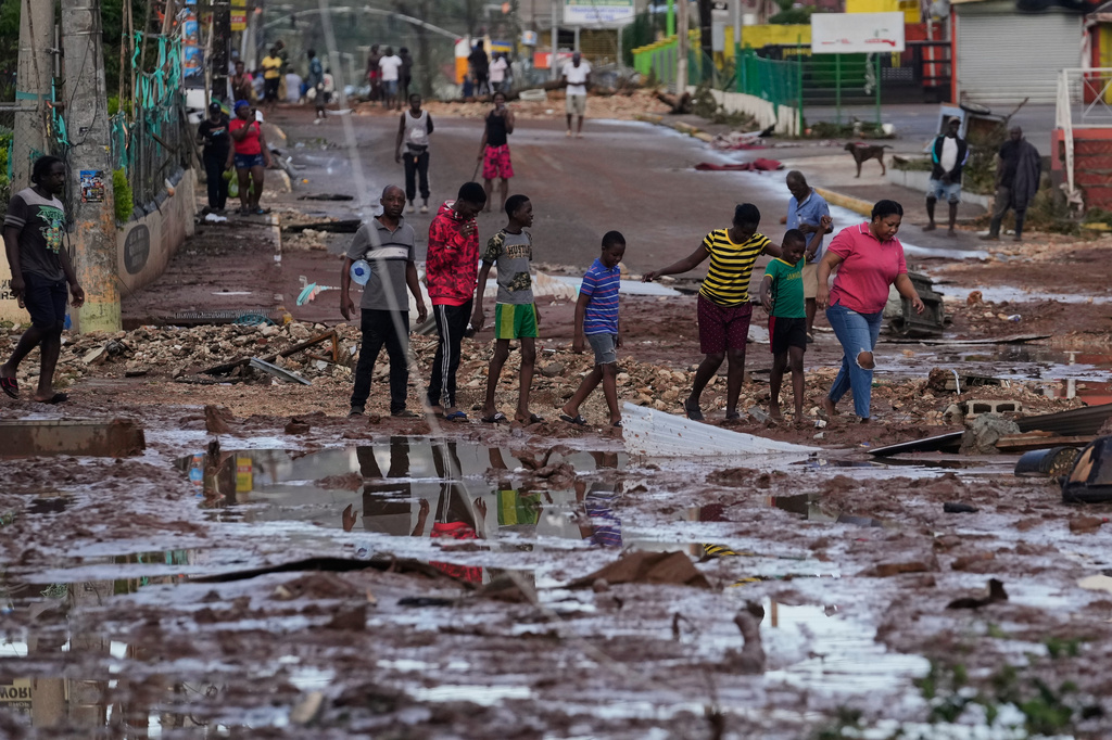 People walk through Santa Cruz, Jamaica, Wednesday, Oct. 29, 2025, after Hurricane Melissa passed. (AP Photo/Matias Delacroix),