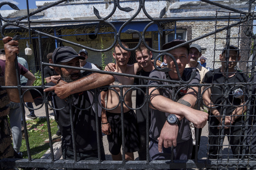 Prisoners stand behind the fence in the barrack's yard in a prison, in the Dnipropetrovsk region, Ukraine, Friday, June 21, 2024. Ukraine is expanding its military recruiting to cope with battlefield shortages more than two years into fighting Russia&rsquo;s full-scale invasion. (AP Photo/Evgeniy Maloletka)