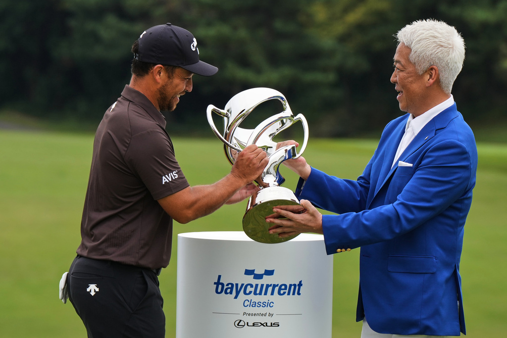 Xander Schauﬀele, left, of the U.S., receives the trophy after he won the Baycurrent Classic golf tournament at the Yokohama Country Club in Yokohama, near Tokyo, Sunday, Oct. 12, 2025. (AP Photo/Hiro Komae)