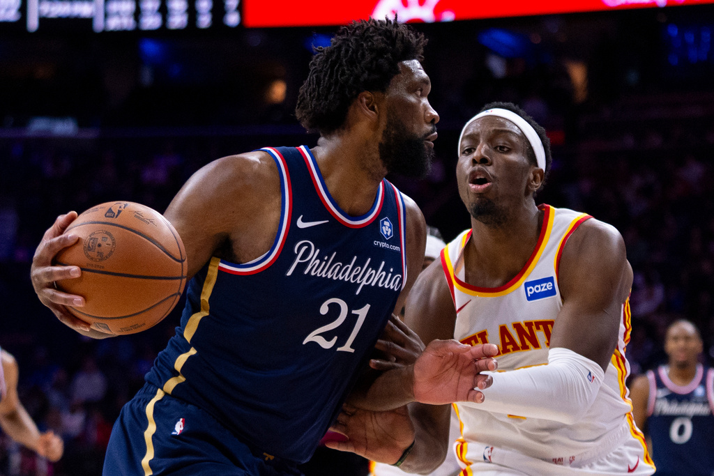 Philadelphia 76ers' Joel Embiid, left, drives to the basket against Atlanta Hawks' Onyeka Okongwu, right, during the second half of an NBA basketball game Sunday, Nov. 30, 2025, in Philadelphia. (AP Photo/Chris Szagola)