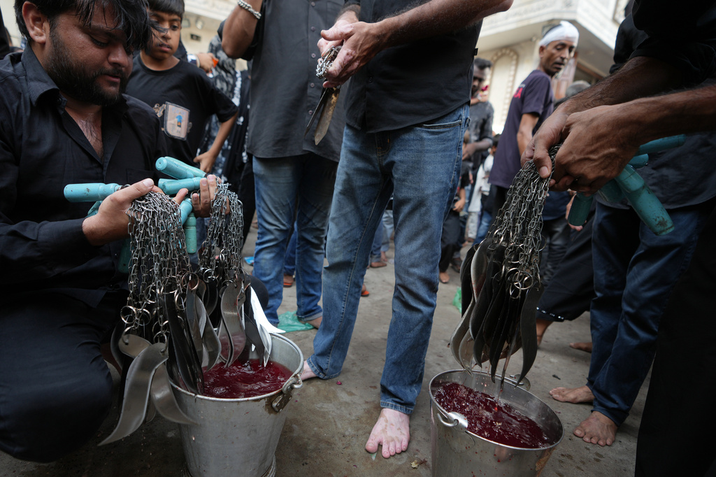 People clean chains, blades and knives after Shiite Muslims flagellate themselves during a Muharram procession in Ahmedabad, India, Tuesday, June 23, 2026. (AP Photo/Ajit Solanki)