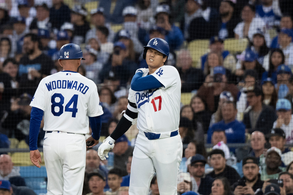 Los Angeles Dodgers' Shohei Ohtani, right, reacts after taking a hit by a pitch during the first inning of a baseball game against the New York Mets in Los Angeles, Monday, April 13, 2026. (AP Photo/Kyusung Gong)