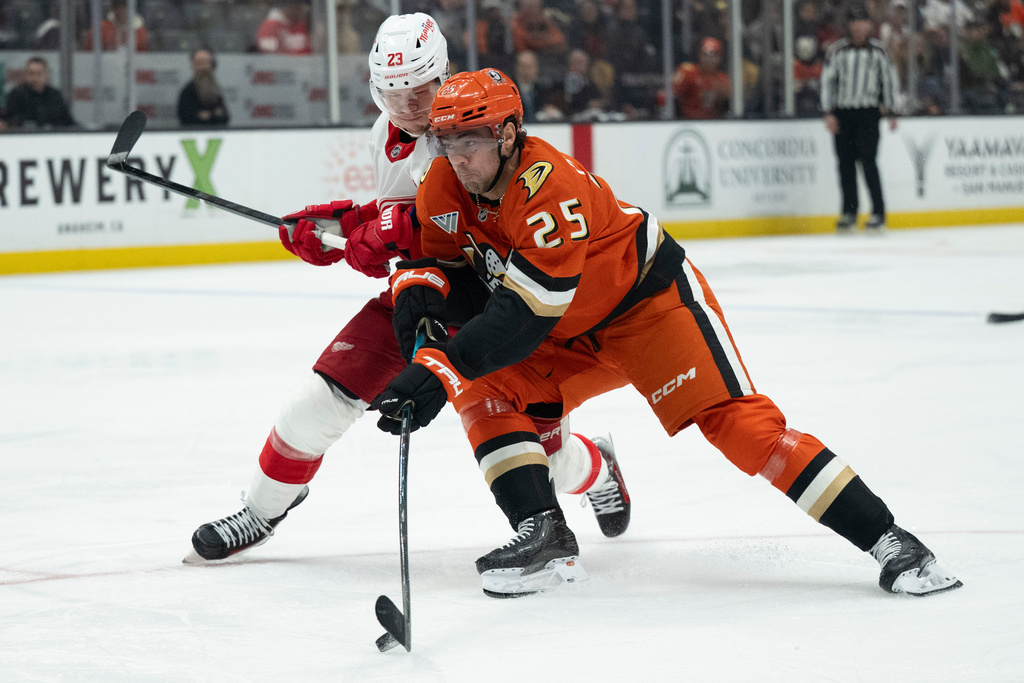 Anaheim Ducks center Ryan Poehling (25) shoots against Detroit Red Wings left wing Lucas Raymond (23) during the third period of an NHL hockey game, Friday, Oct. 31, 2025, in Anaheim, Calif. (AP Photo/Kyusung Gong)