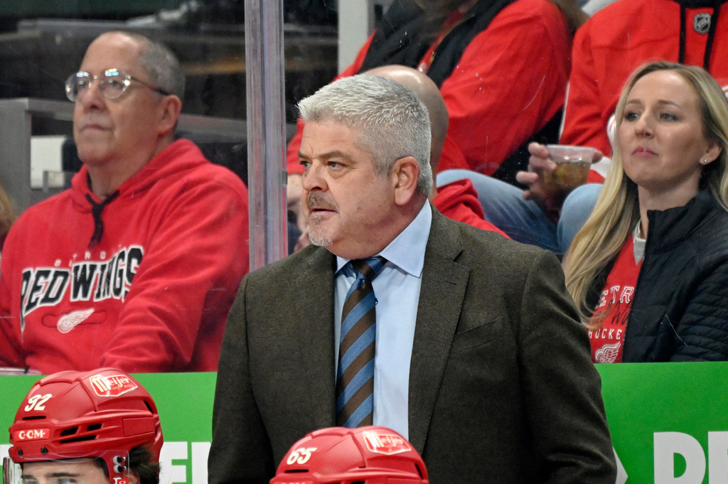 Detroit Red Wings head coach Todd McLellan, center, watches the first period of an NHL hockey game against the New Jersey Devils, Saturday, April 11, 2026, in Detroit. (AP Photo/Jose Juarez)