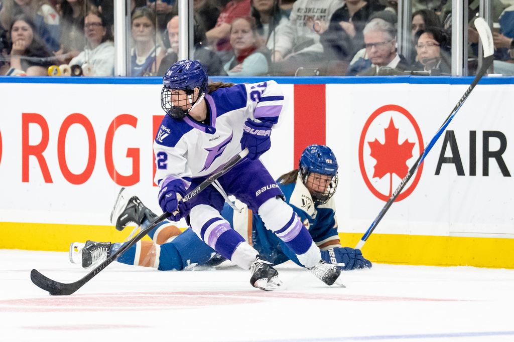 Minnesota Frost's Natalie Buchbinder (22) skates with the puck after Vancouver Goldeneyes' Jenn Gardiner (12) fell during the third period of a PWHL hockey game in Vancouver, British Columbia, Saturday, April 25, 2026. (Ethan Cairns/The Canadian Press via AP)