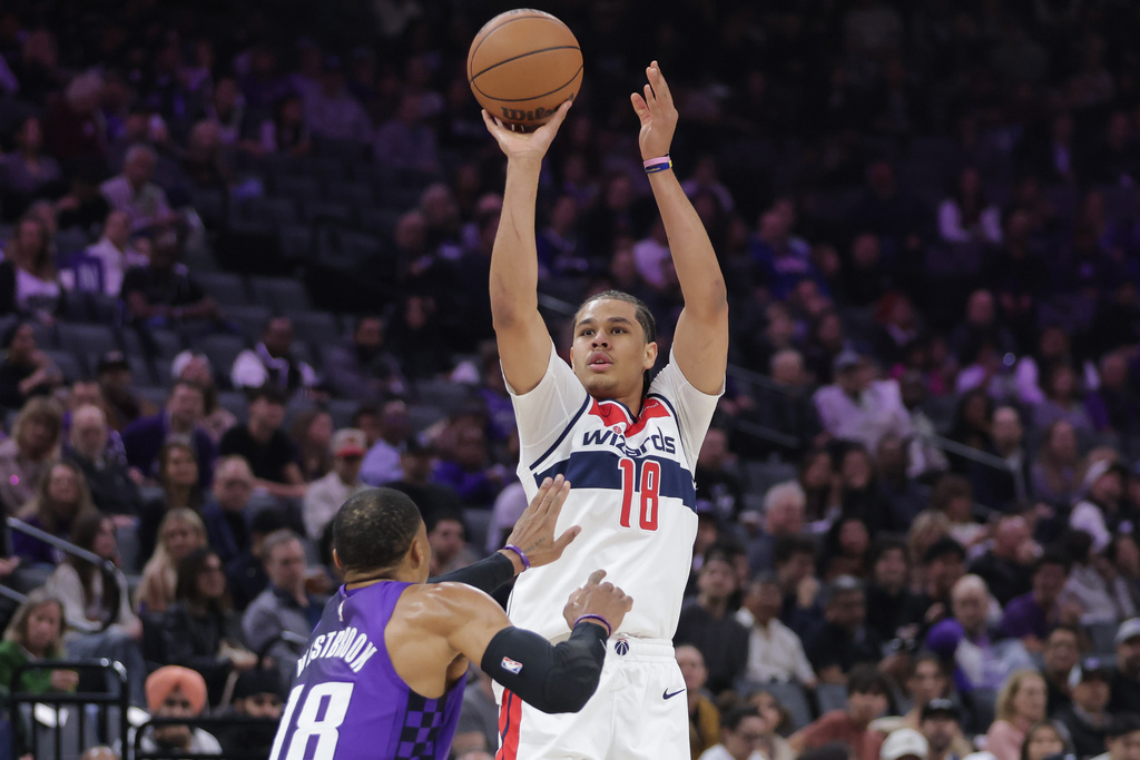 Washington Wizards forward Kyshawn George (18) looks to shoot over Sacramento Kings guard Russell Westbrook (18) during the first half of an NBA basketball game Friday, Jan. 16, 2026, in Sacramento, Calif. (AP Photo/Scott Marshall)