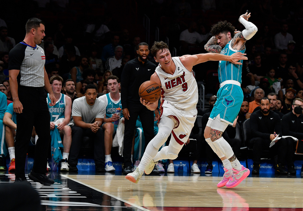 Miami Heat guard Pelle Larsson (9) dribbles past Charlotte Hornets guard Lamelo Ball during the first half of an NBA basketball game, Tuesday, Oct. 28, 2025, in Miami. (AP Photo/Michael Laughlin)