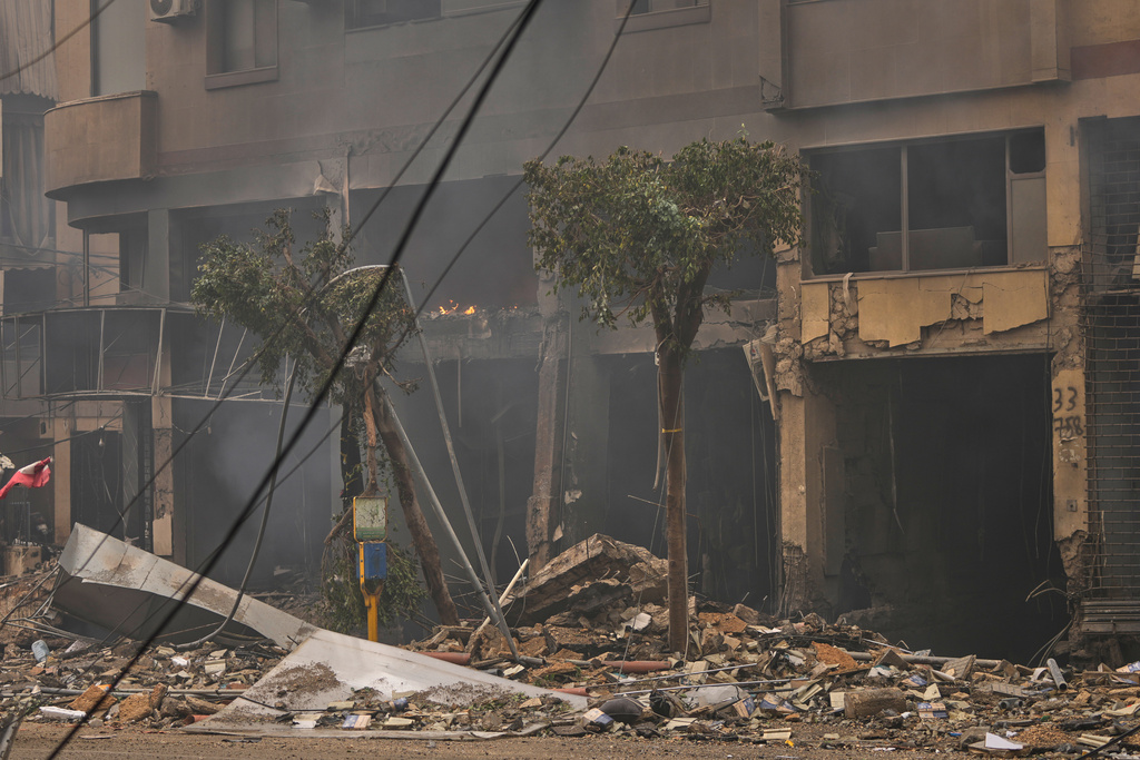 Debris litters the street as smoke rises from buildings damaged in an Israeli airstrike in Dahiyeh, Beirut's southern suburbs, Lebanon, Sunday, March 15, 2026. (AP Photo/Hassan Ammar)