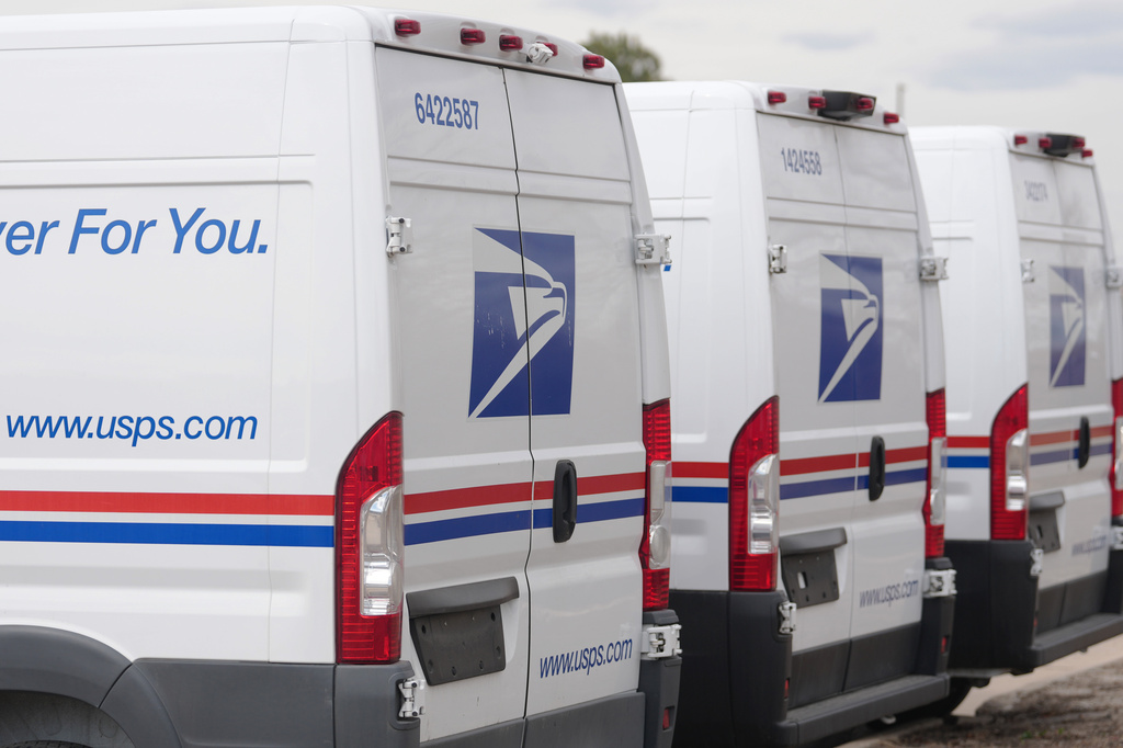 FILE - The United States Postal Service logo is shown on delivery vans parked outside the main post office March 23, 2026, in east Denver. (AP Photo/David Zalubowski, File)