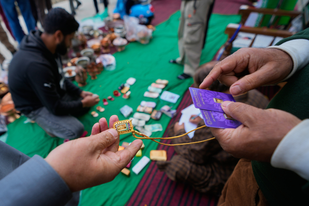 A volunteer examines the authenticity of donated gold jewelry during a relief drive for Iran in Budgam, Indian-controlled Kashmir, Monday, March 23, 2026. (AP Photo/Mukhtar Khan)