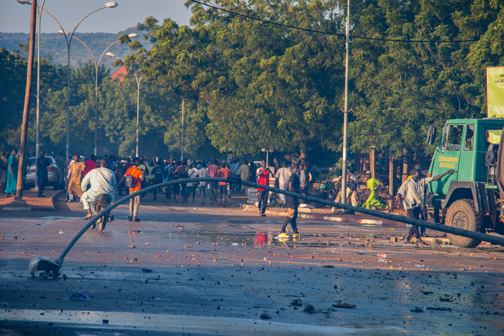 People walk past debris and a damaged streetlight after clashes between police and supporters of presidential candidate Issa Tchiroma in Garoua, Cameroon, Sunday, Oct. 12, 2025, as political parties hold final events ahead of the presidential election. (AP Photo/Welba Yamo Pascal)