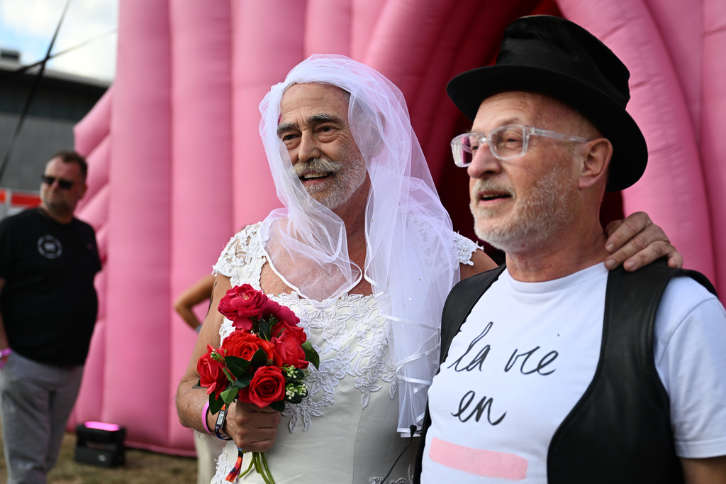 Newlyweds Jan Derksen-Wynn, left, and John Wijfjes pose for photos after tying the knot during a mass wedding ceremony in an inflatable chapel in Amsterdam, Netherlands, Thursday, Aug. 6, 2026, as part of Pride events celebrating 25 years since the Netherlands became the first country in the world to legalize same-sex marriage. (AP Photo/Mouneb Taim)