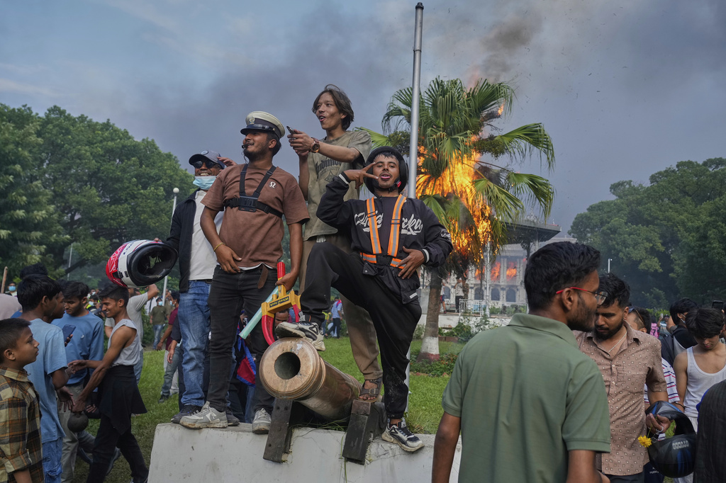 Protesters celebrate at the Singha Durbar, the seat of Nepal's government's various ministries and offices, after it was set on fire during a protest against a social media ban and corruption in Kathmandu, Nepal, Tuesday, Sept. 9, 2025. (AP Photo/Niranjan Shrestha)