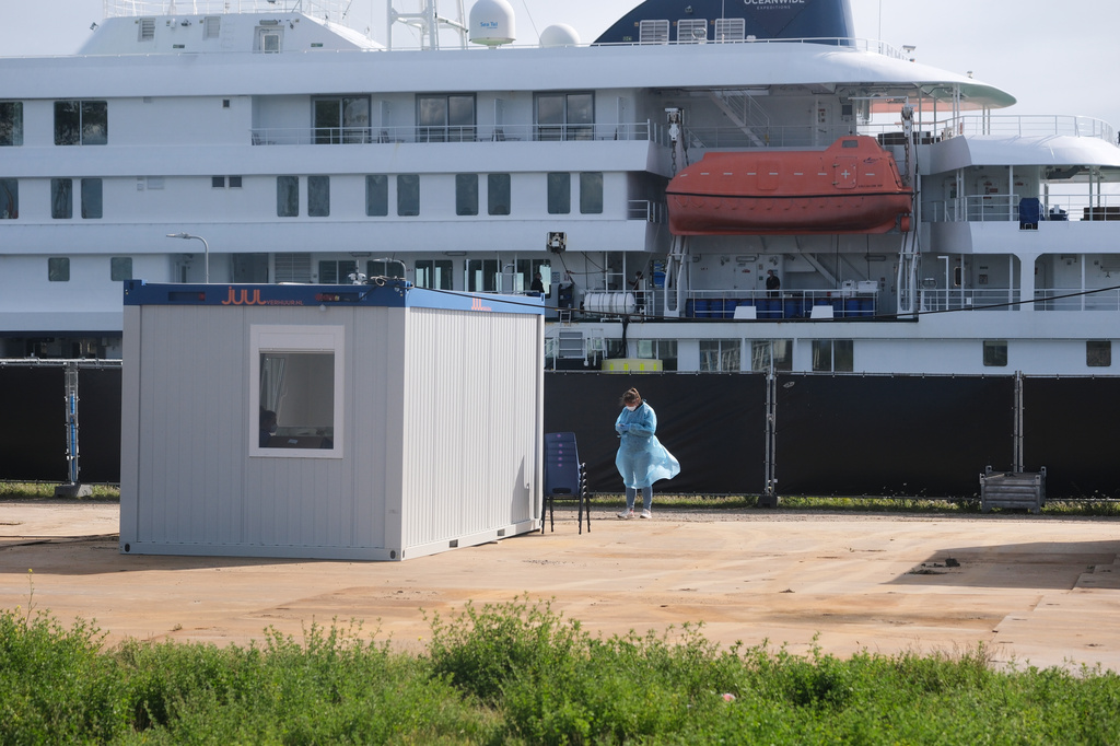 A woman in protective gear stands in front of the MV Hondius cruise ship to check on disembarking crew members after its arrival at the Port of Rotterdam, Netherlands, Monday, May 18, 2026. (AP Photo/Patrick Post)