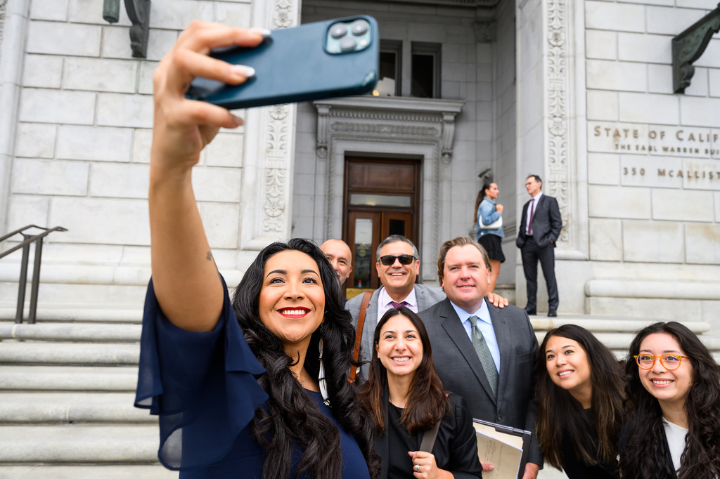 Plaintiff Clarissa Cervantes takes a selfie with legal team members before attending a hearing about Riverside County Sheriff Chad Bianco's seizure and recount of more than half a million 2025 election ballots on Monday, Aug. 24, 2026, in San Francisco. (AP Photo/Noah Berger)