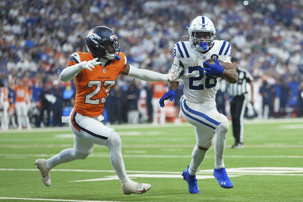 Indianapolis Colts running back Jonathan Taylor (28) runs against Denver Broncos cornerback Jahdae Barron during the second half an NFL football game, Sunday, Sept. 14, 2025, in Indianapolis. (AP Photo/AJ Mast)