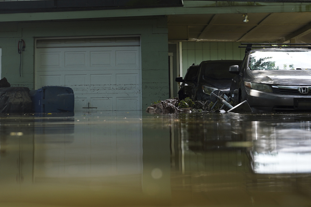 Vehicles sit in water in front of a flooded home in Indianapolis, Sunday, Aug. 16, 2026. (AP Photo/Obed Lamy)