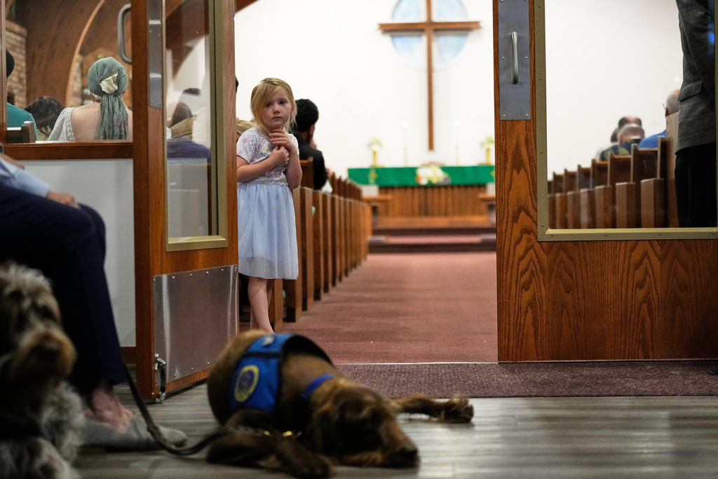 A child looks out from the pew during a service for the Sunday morning shooting at The Church of Jesus Christ of Latter-day Saints in Grand Blanc Township, Mich., Monday, Sept. 29, 2025. (AP Photo/Ryan Sun)