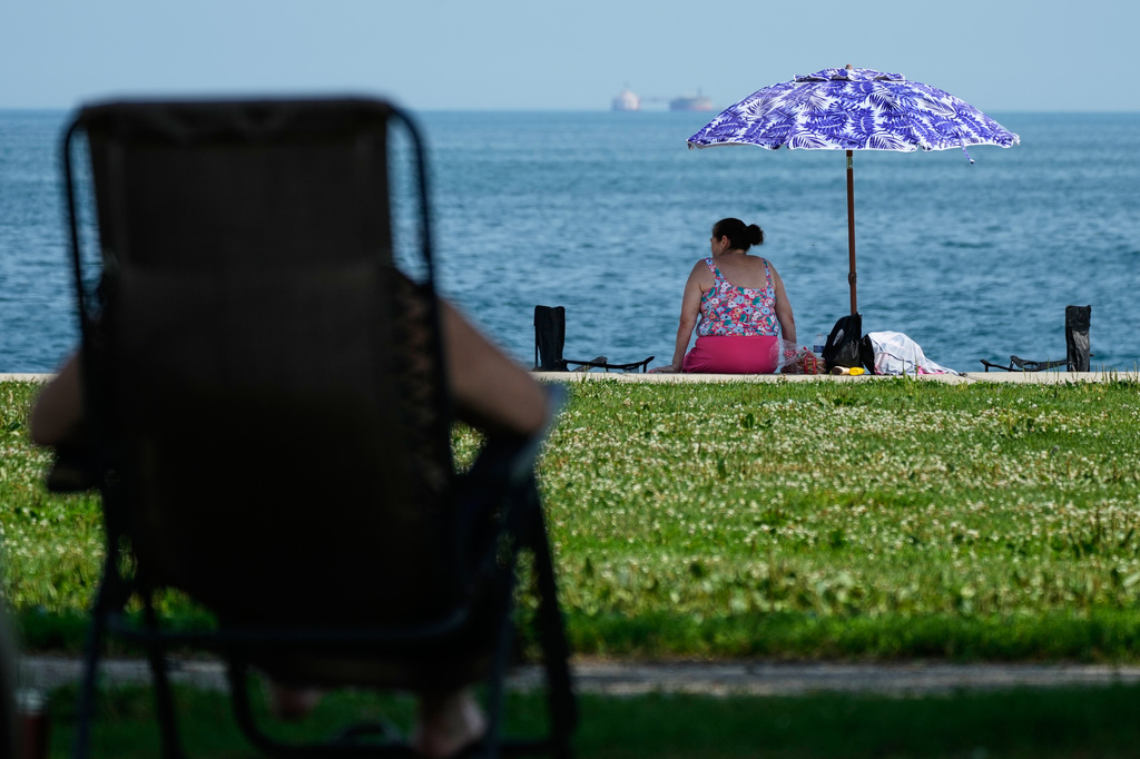 FILE - A woman cools off under a umbrella during hot weather at Montrose beach in Chicago, July 15, 2026. (AP Photo/Nam Y. Huh, File)