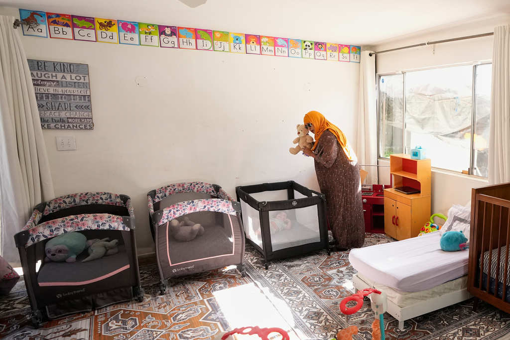 Samsam Khalif shows a child a stuffed animal as she prepares for nap time at her home-based child care center Friday, Jan. 30, 2026, in San Diego. (AP Photo/Gregory Bull)