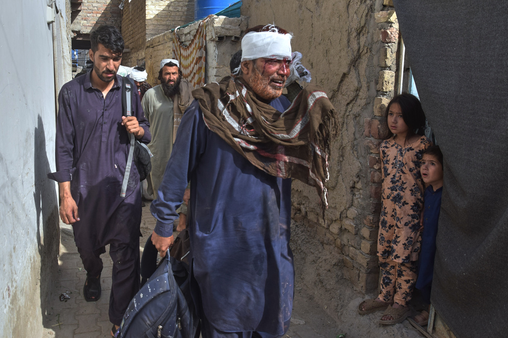 Children look at an injured person passing through an alley near the site of a bomb explosion in Quetta, Pakistan, Sunday, May 24, 2026. (AP Photo/Arshad Butt)