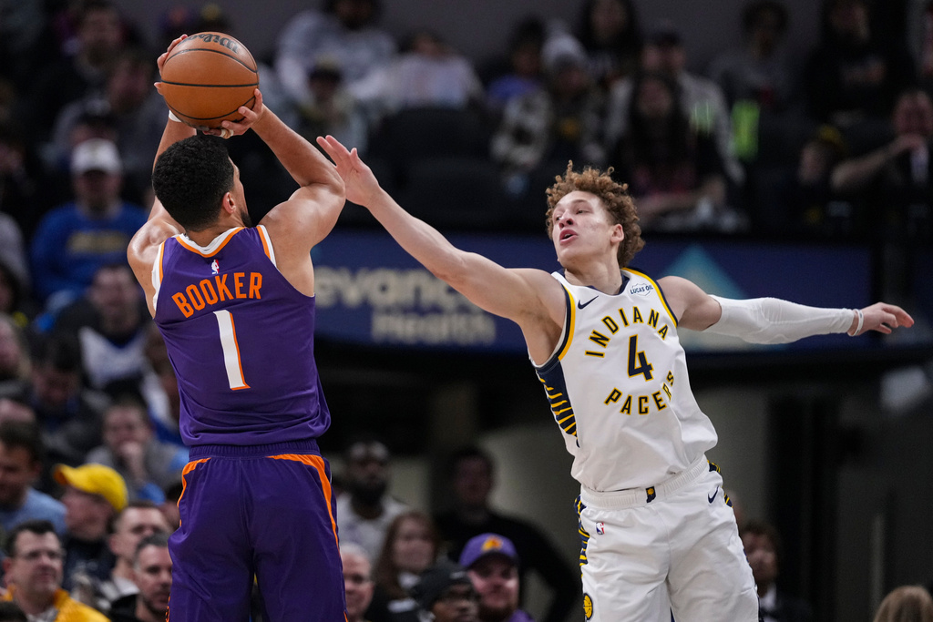 Phoenix Suns guard Devin Booker (1) shoots over Indiana Pacers guard Taelon Peter (4) during the first half of an NBA basketball game in Indianapolis, Thursday, March 12, 2026. (AP Photo/Michael Conroy)