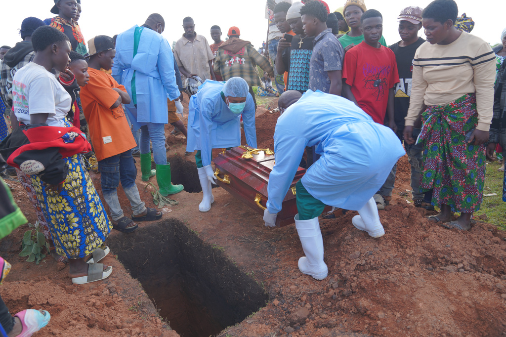 People dressed in protective gear prepare to lower into a grave the coffin containing the remains of 3-year-old Mave Mercienne, who died of Ebola, in Bunia, Ituri province, eastern Congo, Tuesday, Aug. 18, 2026. (AP Photo/Dieudonne Dirole)