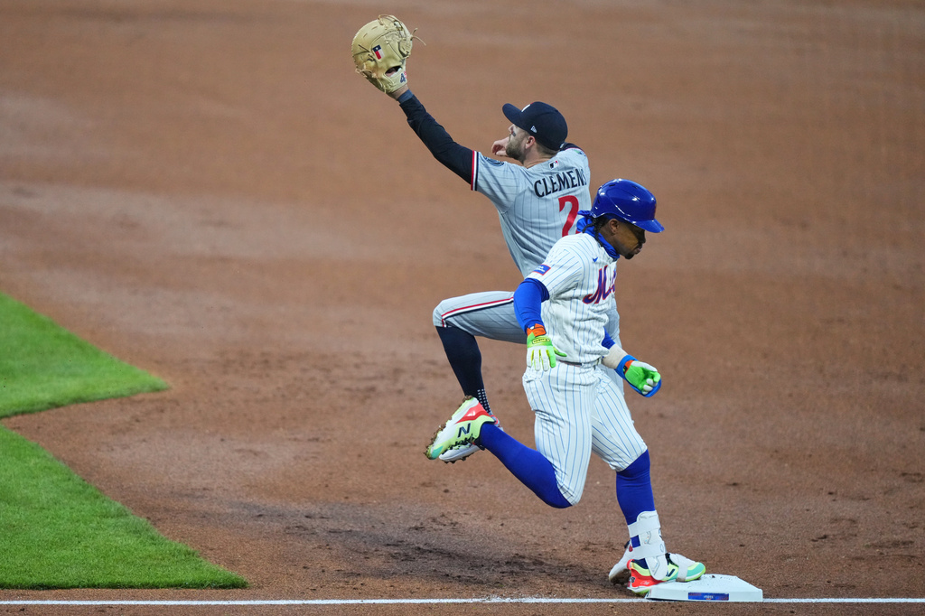New York Mets' Francisco Lindor (12) runs past Minnesota Twins' Kody Clemens (2) to reach first base for a single during the first inning of a baseball game Wednesday, April 22, 2026, in New York. (AP Photo/Frank Franklin II)