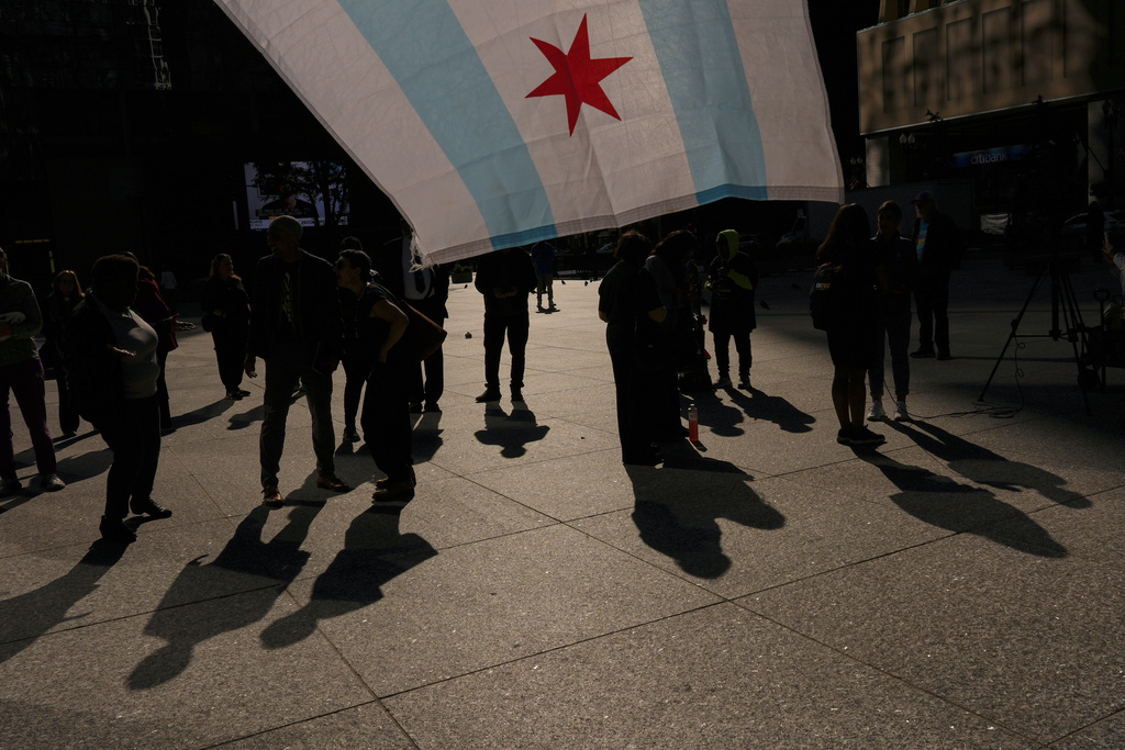 People hold a Chicago flag as they gather near Daley Plaza, Monday, Sept. 8, 2025, in Chicago. (AP Photo/Carolyn Kaster)