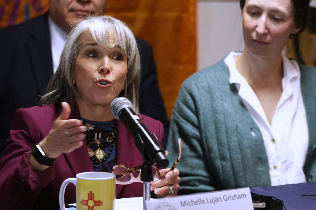 New Mexico Gov. Michelle Lujan Grisham, left, speaks during a news conference, Tuesday, March 10, 2026, in Santa Fe, N.M., after signing legislation that bars federal immigration agents from election polling sites in New Mexico, in a step being considered by several other Democratic-led states. (AP Photo/Morgan Lee)