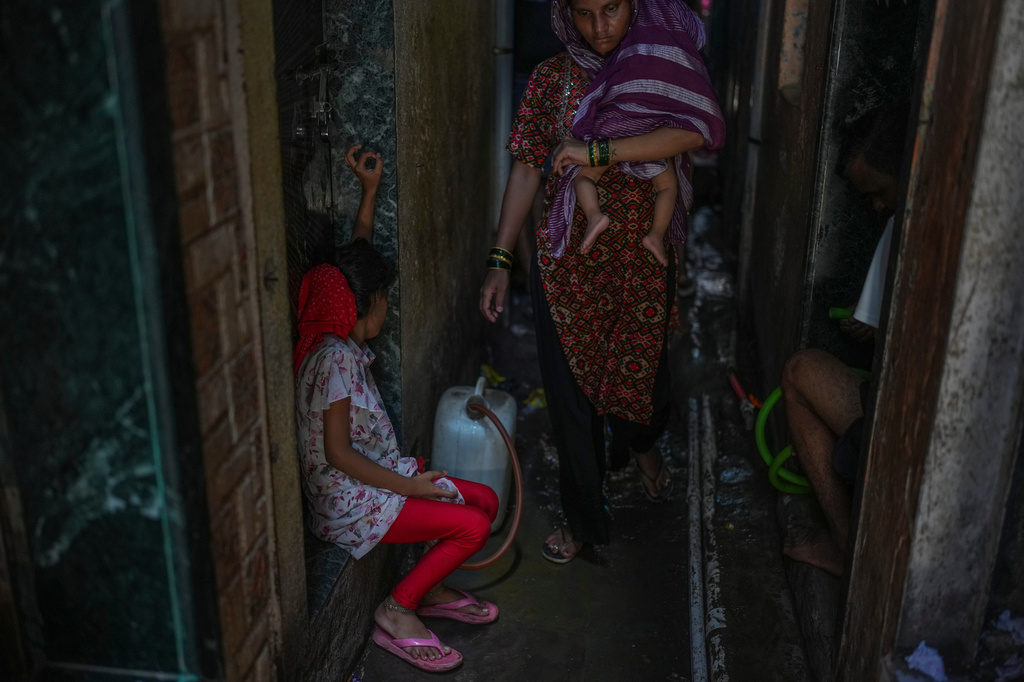 A girl fills water in a narrow lane of a slum settlement in Mumbai, India, Sunday, June 21, 2026. (AP Photo/Rafiq Maqbool)