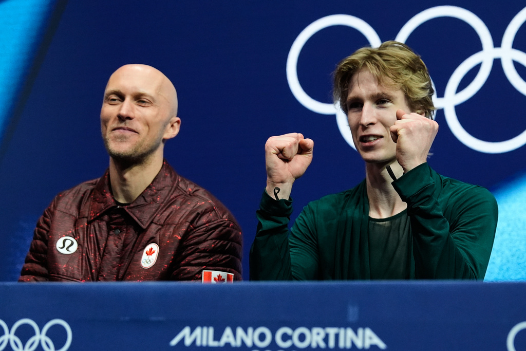 Stephen Gogolev of Canada, right, reacts to his scores after competing during the men's free skate program in figure skating while sitting next to choreographer Benoit Richaud, left, at the 2026 Winter Olympics, in Milan, Italy, Friday, Feb. 13, 2026. (AP Photo/Ashley Landis)