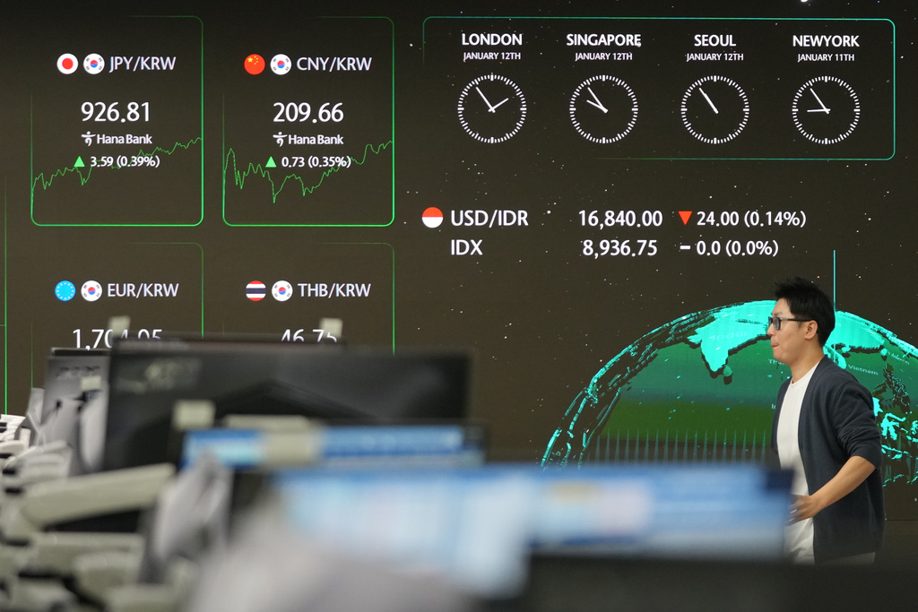 A dealer walks near the screens showing the foreign exchange rates at a dealing room of Hana Bank in Seoul, South Korea, Monday, Jan. 12, 2026. (AP Photo/Lee Jin-man)