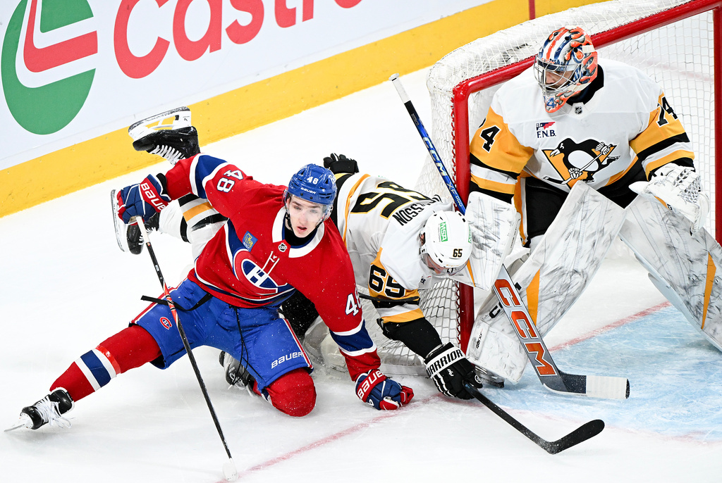 Pittsburgh Penguins goaltender Stuart Skinner, right, looks on as Montreal Canadiens' Lane Hutson (48) and Penguins' Erik Karlsson (65) collide in front of his net during the first period of an NHL hockey game in Montreal, Saturday, Dec. 20, 2025. (Graham Hughes/The Canadian Press via AP)