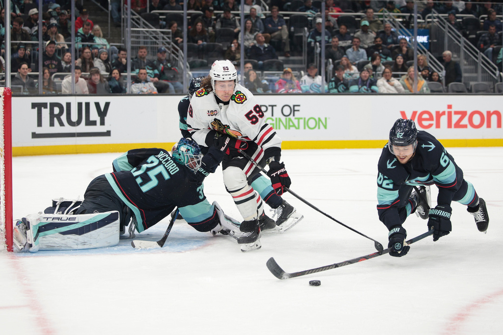Chicago Blackhawks left wing Tyler Bertuzzi tries to score as Seattle Kraken defenseman Brandon Montour (62) blocks a pass and goalie Joey Daccord (35) defends during the second period of an NHL hockey game Monday, Nov. 3, 2025, in Seattle. (AP Photo/Jason Redmond)