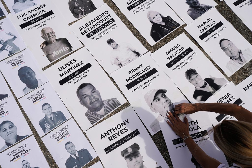 Jacklin Ibarreto, whose father Miguel Ibarreto is detained, lays out photos of political prisoners at the Central University of Venezuela in Caracas, Venezuela, Tuesday, Jan. 13, 2026. (AP Photo/Matias Delacroix)