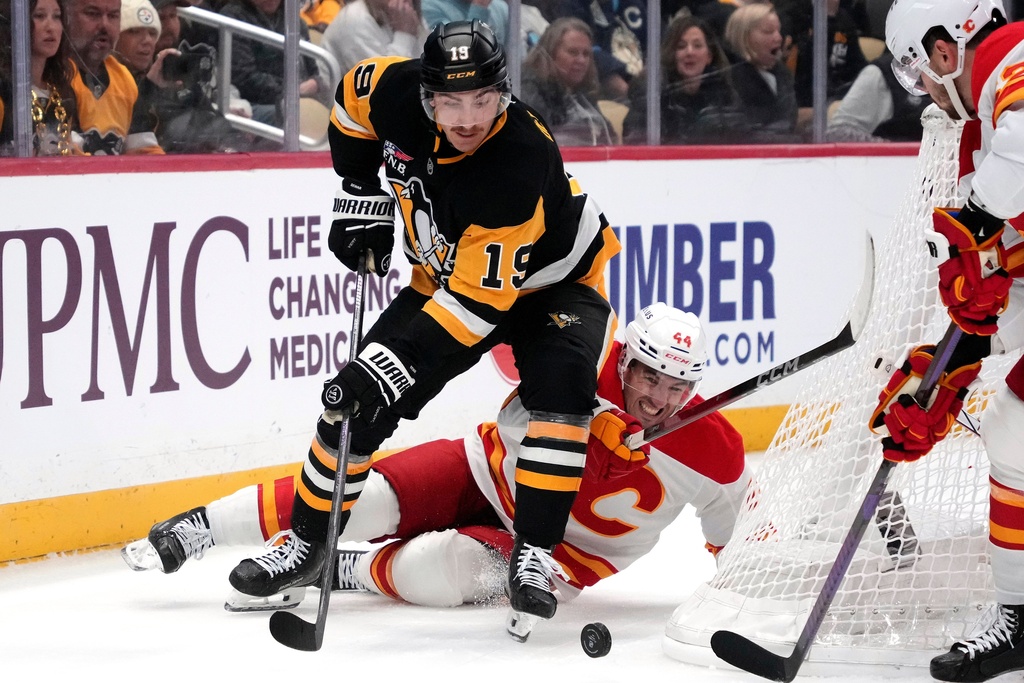 Pittsburgh Penguins' Connor Dewar (19) checks Calgary Flames' Joel Hanley (44) off the puck during the second period of an NHL hockey game in Pittsburgh, Saturday, Jan. 10, 2026. (AP Photo/Gene J. Puskar)
