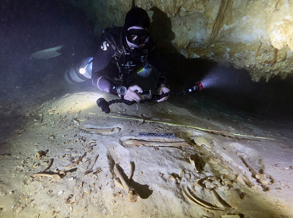 In this handout photo provided by the National Institute of Anthropology and History, underwater archaeologist Octavio del Río takes photos of the remains of a prehistoric human skeleton discovered inside the flooded cave system in Actun, near Tulum, Mexico, Nov. 18, 2025. (Eugenio Acevez/National Institute of Anthropology and History via AP)