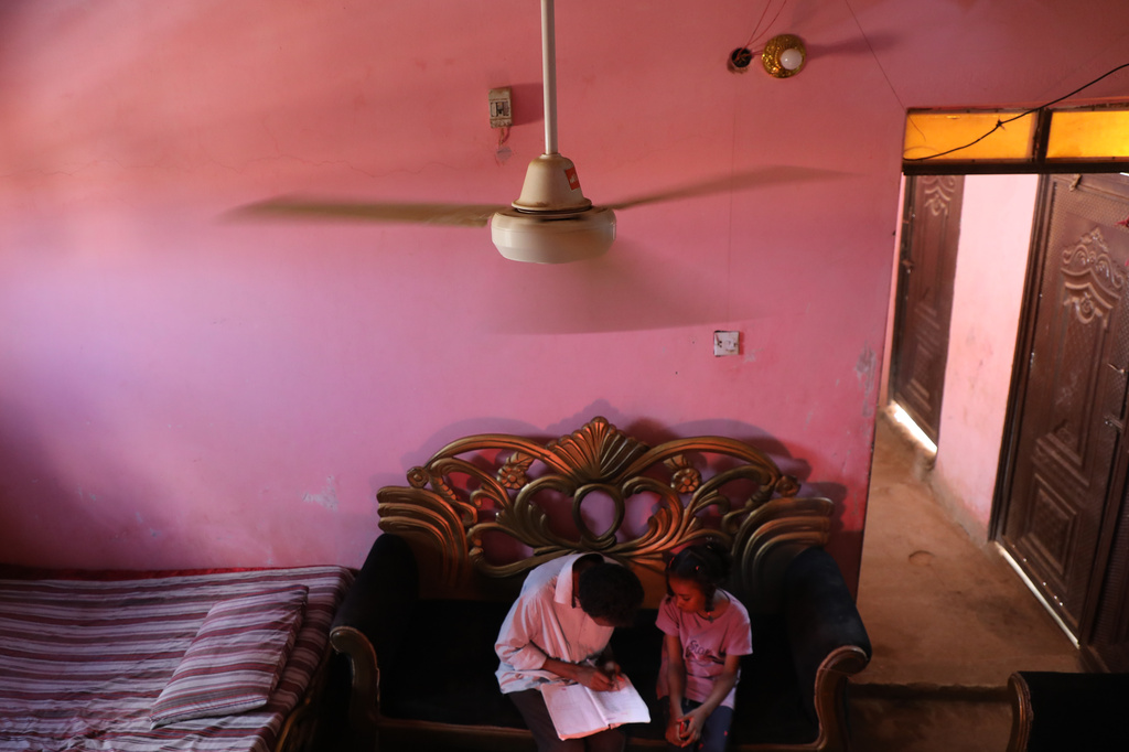 Al-Hodabi Yassin, a diabetes patient, teaches his daughter during a power cut, in Omdurman, on the outskirts of Khartoum, Sudan, Friday, July 24, 2026. (AP Photo/Mohnd Blal)