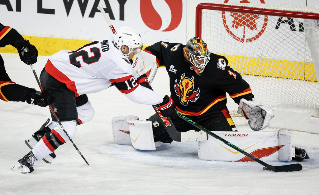 Ottawa Senators' Shane Pinto, left, has his shot stopped by Calgary Flames goalie Devin Cooley during the third period of an NHL hockey game in Calgary on Thursday, March 5, 2026. (Jeff McIntosh/The Canadian Press via AP)