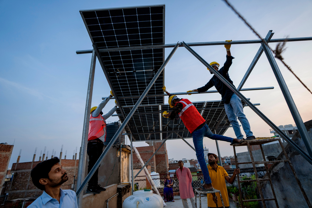 FILE - Workers install solar panels on a rooftop of a home in Prayagraj, India, Monday, Oct. 14, 2024. (AP Photo/Rajesh Kumar Singh, File)