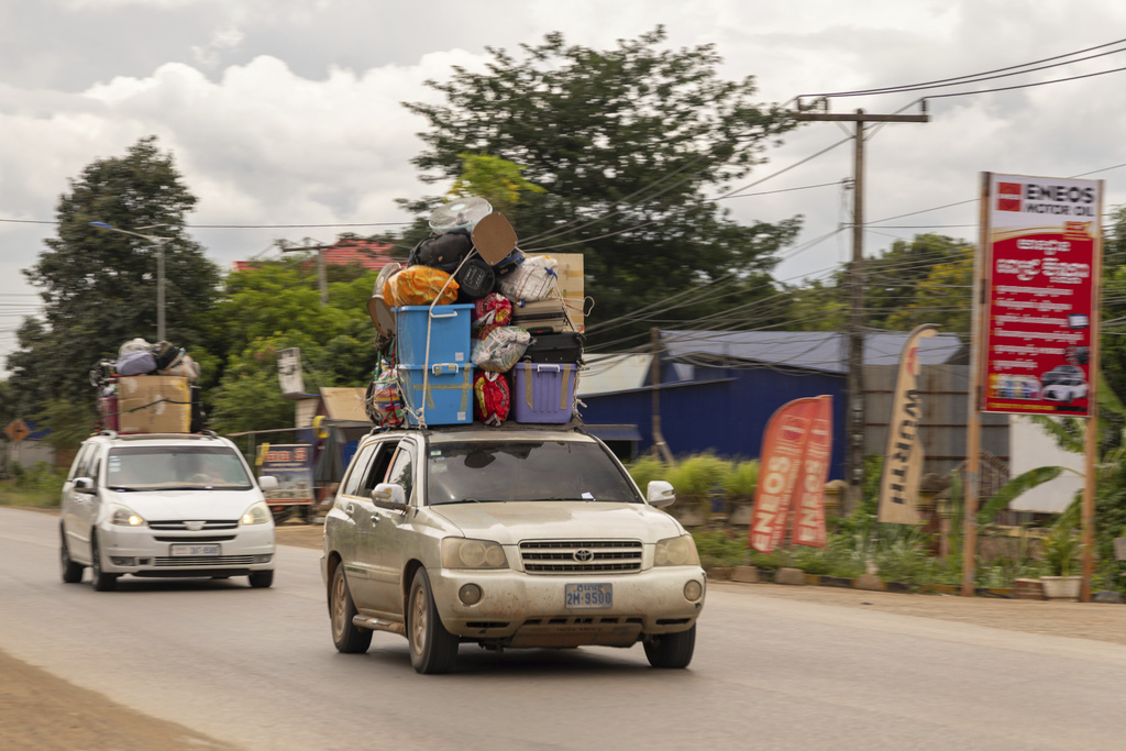 Shuttles packed to the brim with Cambodian migrant workers and their belongings drive away from the Daung International Border Check Point between Cambodia and Thailand, in in Kamrieng, on Wednesday, Aug. 6, 2025. (AP Photo/Anton L. Delgado)