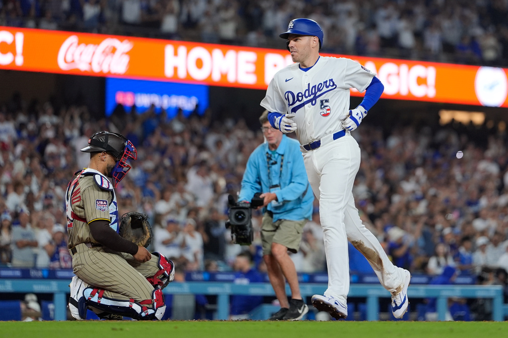Los Angeles Dodgers' Freddie Freeman, right, scores after hitting a solo home run as San Diego Padres catcher Luis Campusano watches during the sixth inning of a baseball game Saturday, July 4, 2026, in Los Angeles. (AP Photo/Mark J. Terrill)