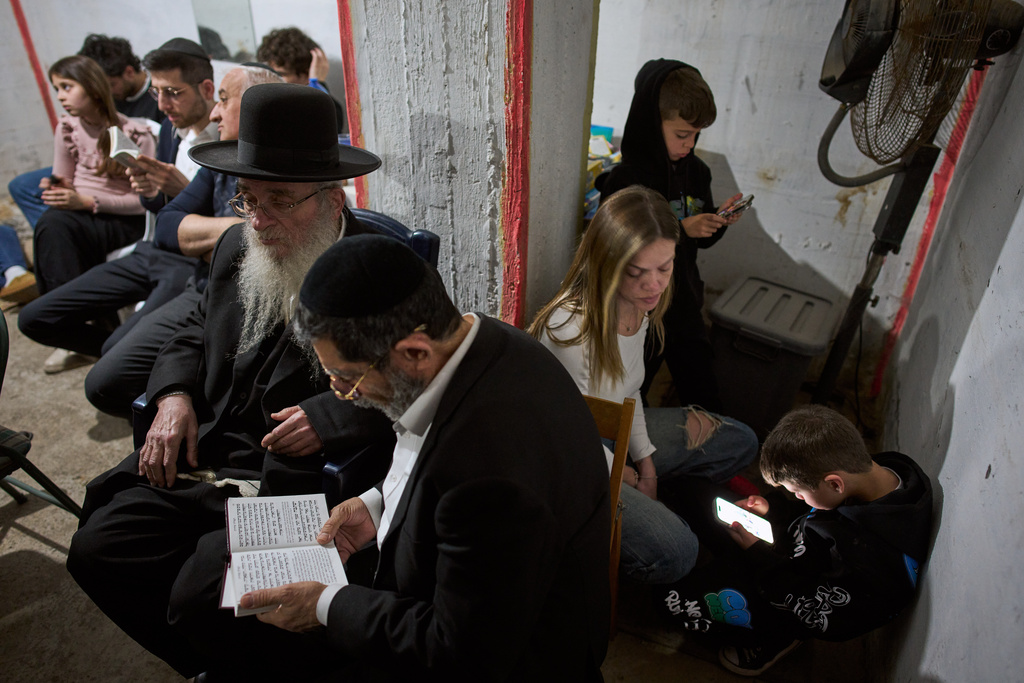 People take cover in an underground bomb shelter as air raid sirens warn of incoming Iranian missile strike, in Ramat Gan, Israel, Wednesday, March 11, 2026. (AP Photo/Oded Balilty)