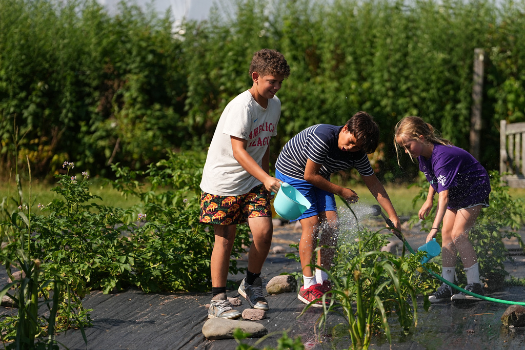 Nicholas Toska, 11, center, of Harrison, N.Y., who has juvenile idiopathic arthritis, waters a garden with fellow campers at the Frost Valley YMCA sleepaway camp in Claryville, N.Y., Wednesday, July 30, 2025. The camp partnered with Children's Hospital at Montefiore so kids with autoimmune diseases could attend for the first time. (AP Photo/Matt Rourke)
