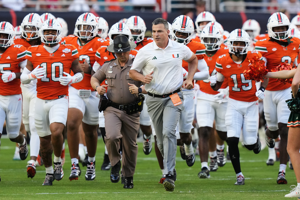 Miami head coach Mario Cristobal, center, runs onto the field before an NCAA college football game against North Carolina State, Saturday, Nov. 15, 2025, in Miami Gardens, Fla. (AP Photo/Lynne Sladky)