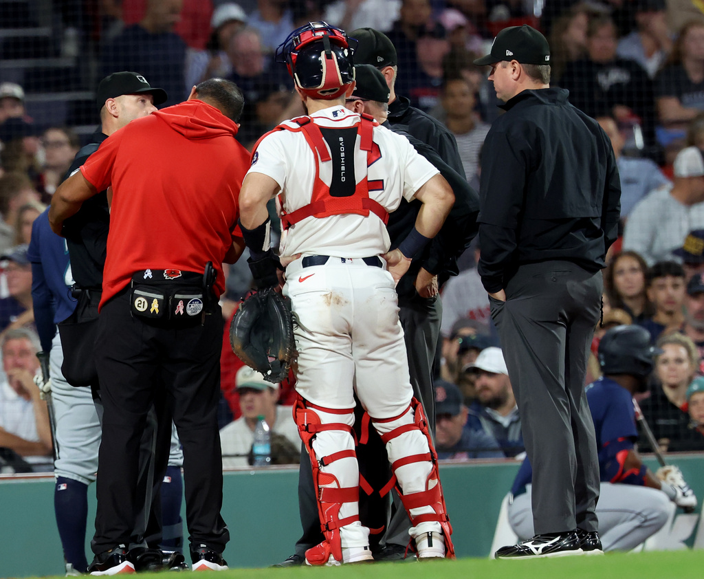 A game delay was called after the home plate umpire, far left, was hit by a pitch during the sixth inning of a baseball game between the Boston Red Sox and Seattle Mariners, Tuesday, Sept. 1, 2026, in Boston. (AP Photo/Mark Stockwell)