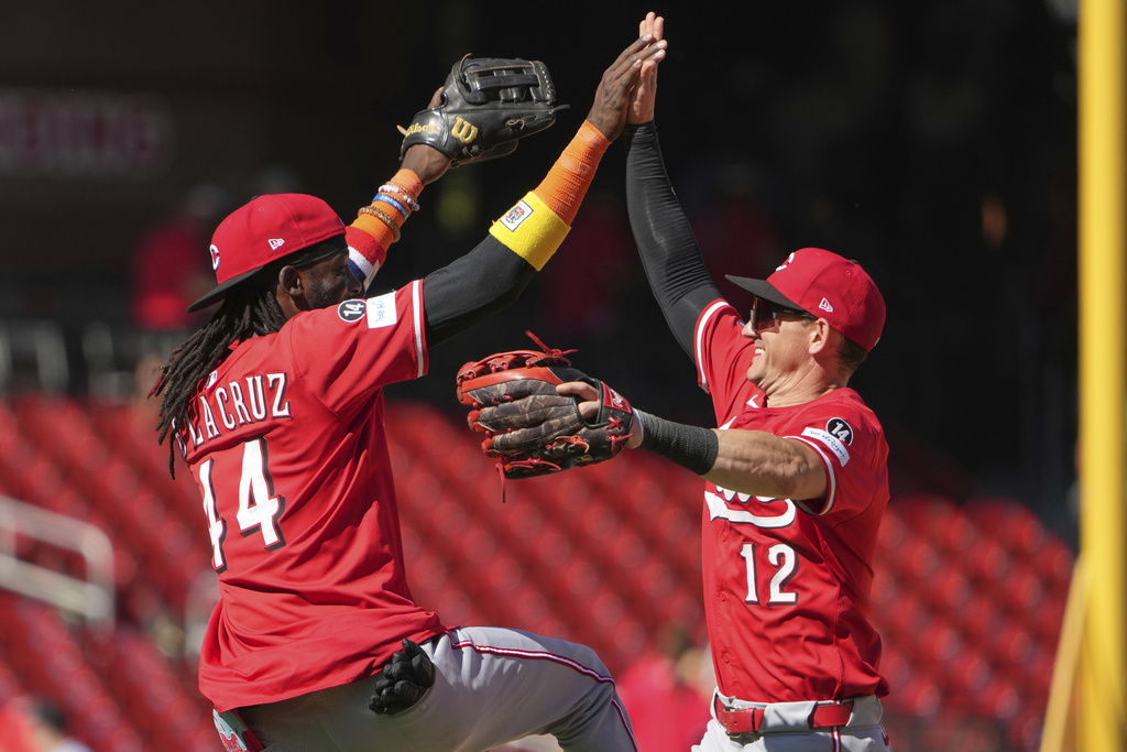 Cincinnati Reds' Austin Hays (12) and Elly De La Cruz (44) celebrate a victory over the St. Louis Cardinals following a baseball game against the St. Louis Cardinals Wednesday, Sept. 17, 2025, in St. Louis. (AP Photo/Jeff Roberson)