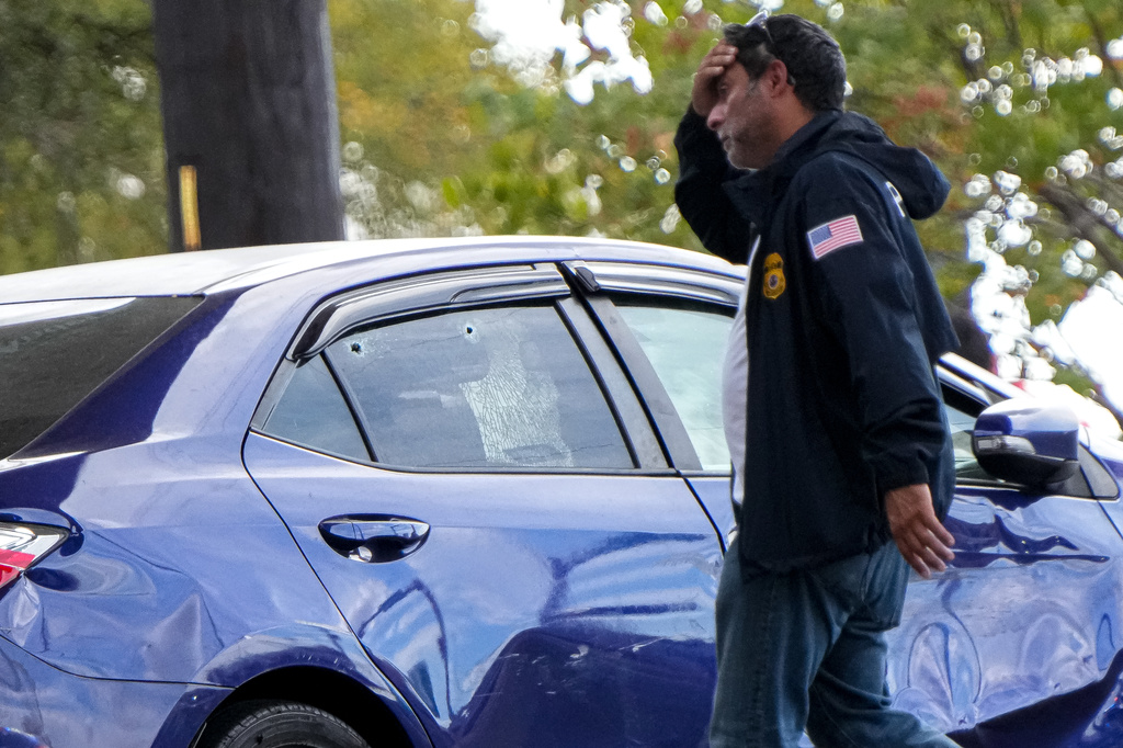 A federal agent walks past a vehicle with a damaged door and holes in the window after a man was shot in his vehicle by an ICE officer, Sunday, Sept. 20, 2026, in Austin, Texas. (Aaron E. Martinez /Austin American-Statesman via AP)