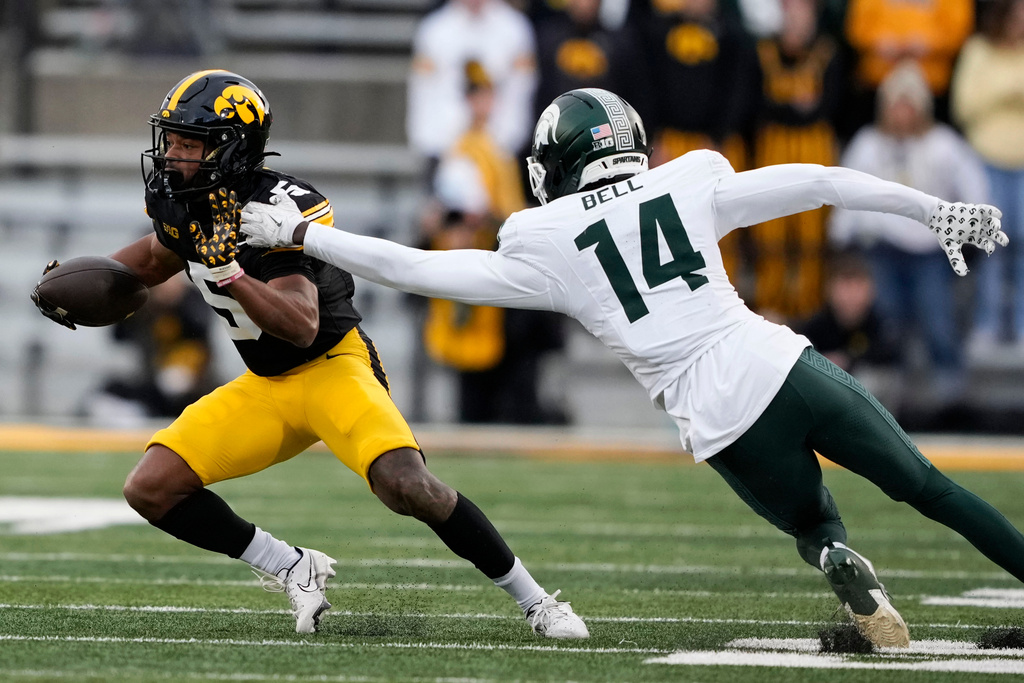 Iowa wide receiver Jacob Gill (5) runs from Michigan State defensive back Malcolm Bell (14) after catching a pass during the first half of an NCAA college football game, Saturday, Nov. 22, 2025, in Iowa City, Iowa. (AP Photo/Charlie Neibergall)